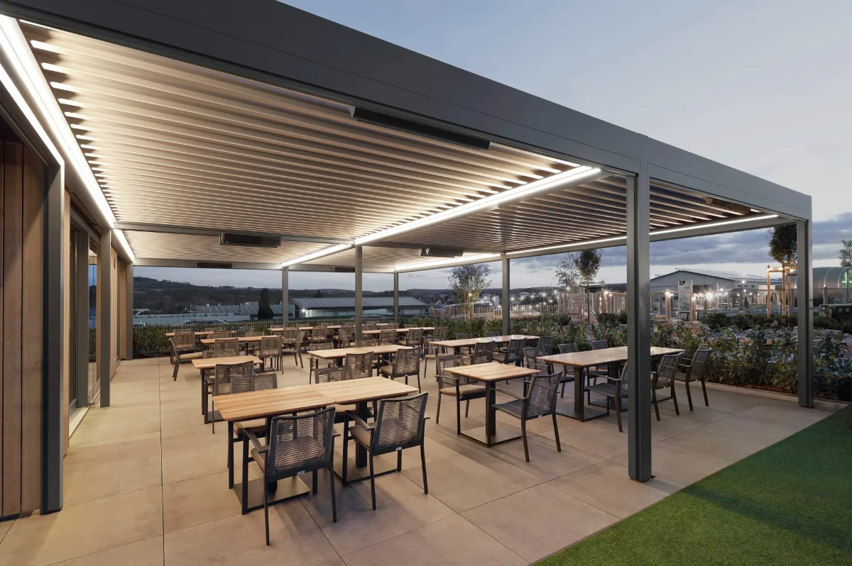 Großes Lamellendach über einem ausladenden Terrassenbereich mit mehreren Tischgruppen